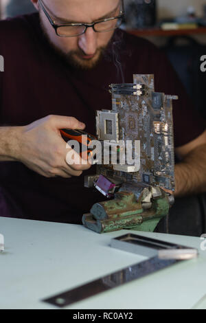 Repair motherboard. Service technician changes capacitor. Troubleshooting. Stock Photo