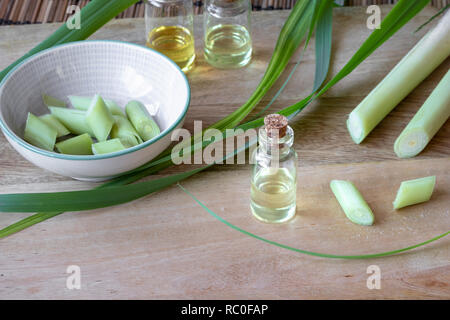 lemongrass essential oil in the bottle, with fresh lemongrass leaves, on  the wooden table Stock Photo