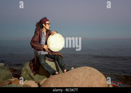 Portrait of an Asian man playing shaman drum, Dahab, Egypt Stock Photo