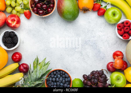 Healthy fruit background frame, strawberries raspberries oranges plums apples kiwis grapes blueberries mango persimmon on the white table Stock Photo
