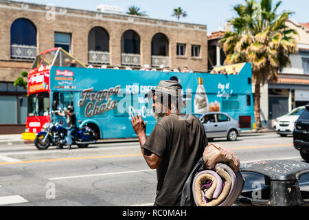 Sunset Boulevard, traffic jam and homeless man walking through the street, Los Angeles, Hollywood, California, May 10, 2018 Stock Photo