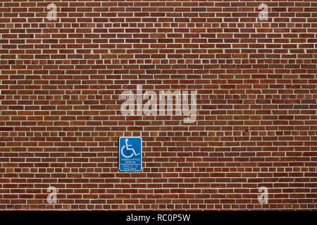 Vintage red brick wall background in traditional common bond pattern and attached handicap parking sign has a rustic grunge look Stock Photo