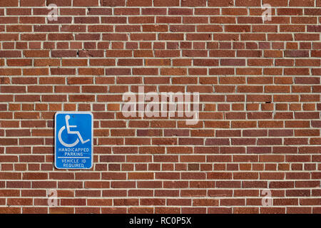 Vintage red brick wall background in traditional common bond pattern and attached handicap parking sign has a rustic grunge look Stock Photo