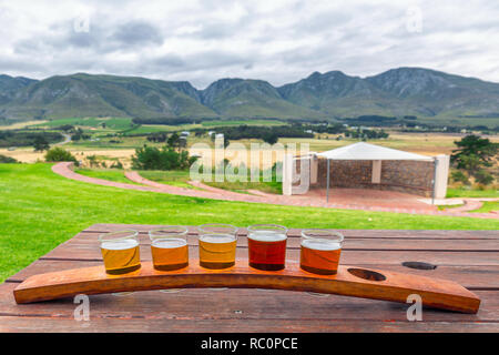 Beer tasting glasses on a wooden tray outside the brewery with a beautiful view of the mountains in South Africa Stock Photo