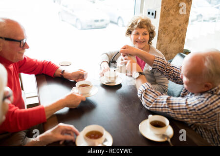 Positive senior friends drinking tea in cafe Stock Photo