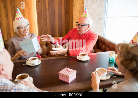 Birthday senior man accepting gifts from friends Stock Photo