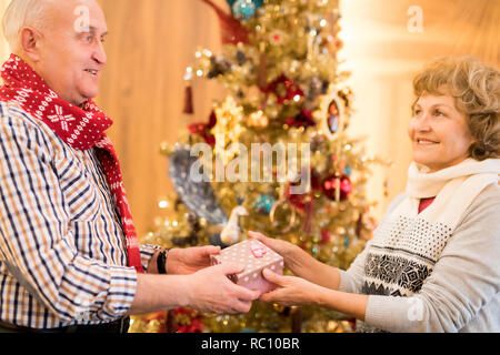 Happy elderly man giving gift to beloved woman Stock Photo