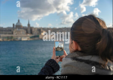 woman tourist taking a photo on her iphone of Valletta in Malta. Stock Photo