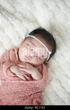 Newborn baby sleeping in bed on soft white blanket Stock Photo