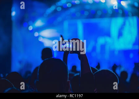 People enjoying rock concert and taking photos with cell phone at music festival. Stock Photo