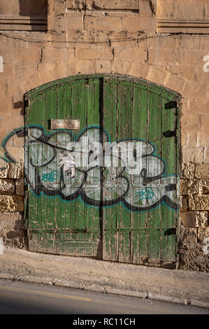 old weathered green garage door in a street in Silema, Malta.