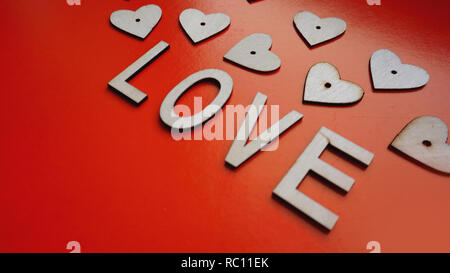 Valentines Day background with red hearts and letters love - made of wood on red Stock Photo