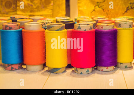 Background with a lot of colorful coils with threads. Bobbins are stacked in three rows, one on the other. The winding is erratic. Multicolored thread Stock Photo