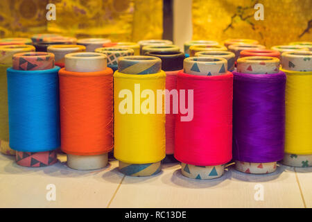 Background with a lot of colorful coils with threads. Bobbins are stacked in three rows, one on the other. The winding is erratic. Multicolored threads Stock Photo
