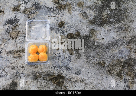 cream puffs in box plastic on the cement floor old with copy space Stock Photo