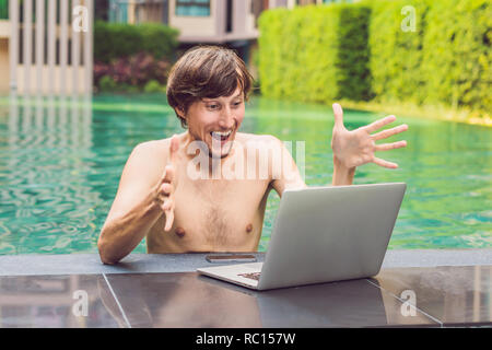 Young freelancer working on vacation next to the swimming pool Stock Photo