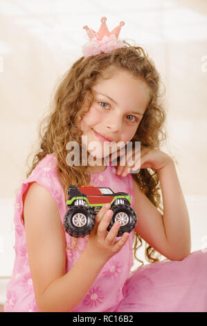 Happy little girl wearing a pink princess dress and holding a gun and wearing a hat and boy clothes Stock Photo
