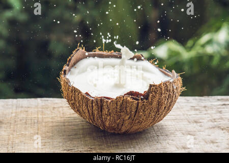 Coconut fruit and milk splash inside it on a background of a palm tree Stock Photo