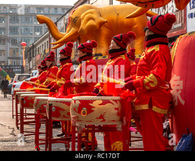 Women in red golden outfits drumming during the ceremonial of the opening of a store in Hunchun city of China, Jilin Province in the Yanbian Prefecture Stock Photo