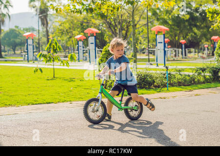 Little boy on a bicycle. Caught in motion, on a driveway. Preschool child's first day on the bike. The joy of movement. Little athlete learns to keep balance while riding a bicycle Stock Photo