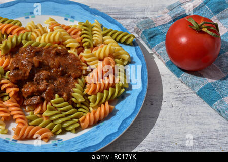 Delicious homemade colorful pasta whit meat sauce and fresh tomato at white wooden background - Image Stock Photo