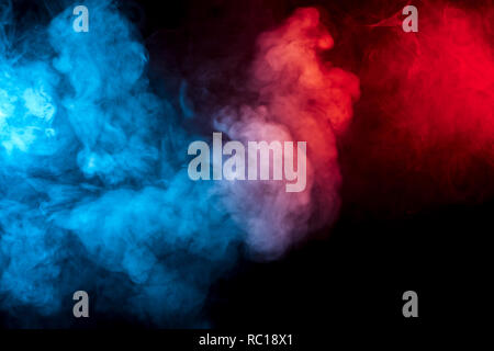 Clouds of isolated colored smoke: blue, red, orange, pink; scrolling on a black background in the dark close up. Stock Photo