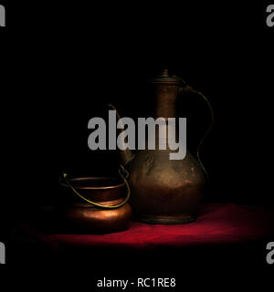 Copperware. Teapot or coffee pot or kettle...maybe MIddle Eastern. On red cloth with bowl. Stock Photo