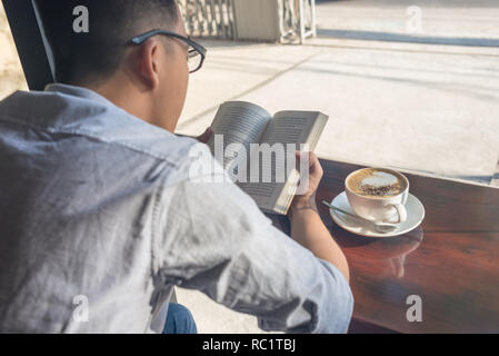Young man reading book and drinking coffee Stock Photo