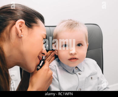 audiologist doctor doing an ear exam with otoscope to little boy Stock Photo