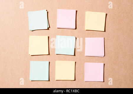 Multi colored notepads laying on a wooden plank board surface with copy space Stock Photo