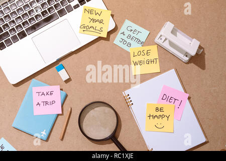 Magnifier glass and sticky note written new year goal word on wooden table Stock Photo