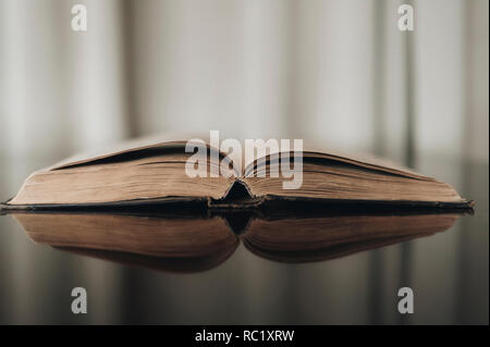 Opened old book with reflected in brown surface Stock Photo