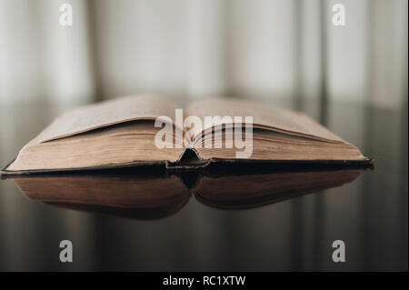 Opened old book with reflected in brown surface Stock Photo
