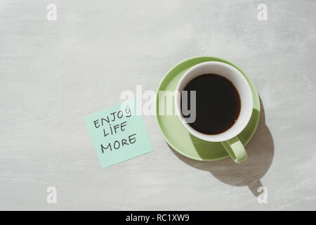 Paper note stick on green coffee mug with text - Enjoy life more Stock Photo