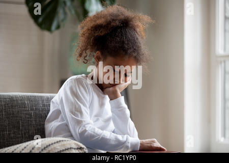 Upset little african girl feeling sad sitting alone at home Stock Photo