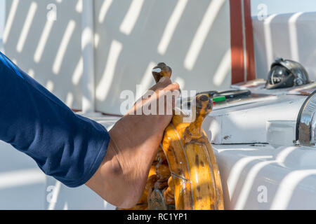 People at the helm of a white yacht. A man Arab controls the yacht. Foot on the yacht steering wheel Stock Photo