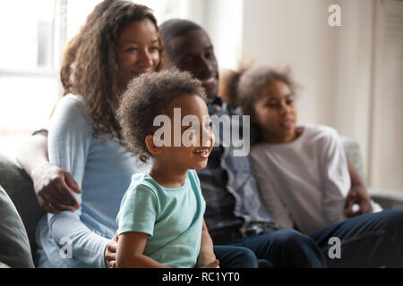 Happy black family with children sitting on couch watching tv Stock Photo