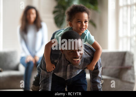 Black dad giving child piggyback ride carrying son on back Stock Photo