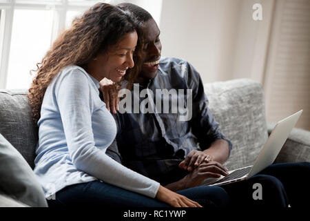 Cheerful black couple having fun in social media using laptop Stock Photo