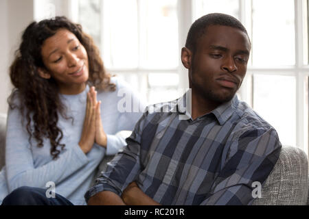 Guilty african woman apologizing asking black husband for forgiv Stock Photo