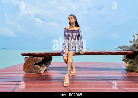 Beautiful woman posing - sitting on bench, looking at camera and pensive Stock Photo