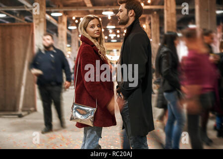 Stroll through the market together. Happy young joyful couple standing in rows at small street market. Autumn season, blond haired woman looking to th Stock Photo