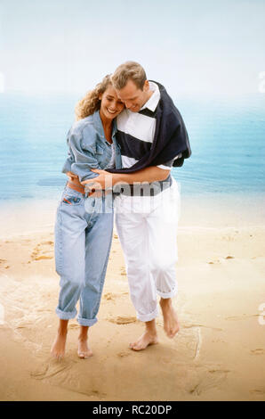 Young couple walking together on sandy beach. Stock Photo