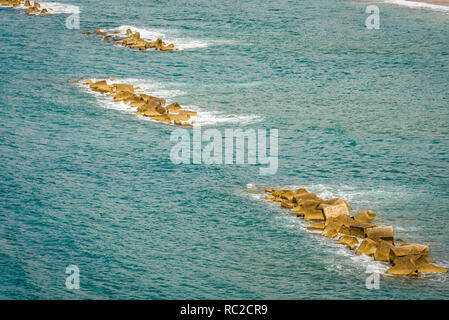 Sea waves crashing on artificial concrete breakwater. Seascape with wave breakers to protect the coast. Stock Photo