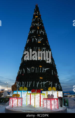 Night view of festive decorated luminous Christmas tree in snowy town Happy New Year. Stock Photo