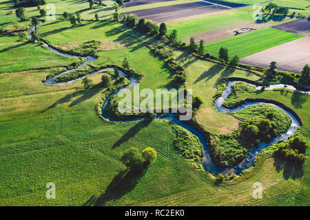 A winding river surrounded by green meadows Stock Photo
