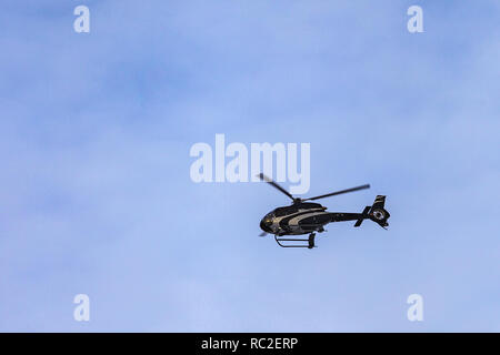 a black helicopter flies against the sky Stock Photo