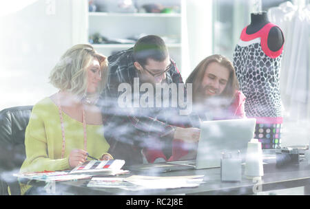 view from behind glass.group of designers working on new sketches Stock Photo