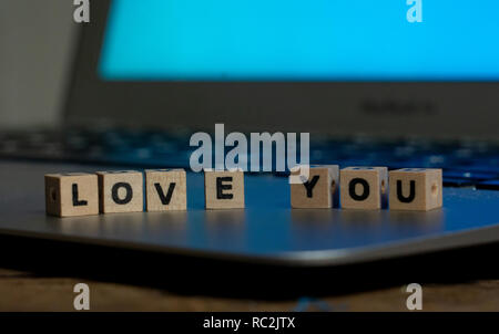 Conceptual image of text Love you in wood blocks on computer with mood romantic screen light background in Valentines day internet connection technolo Stock Photo