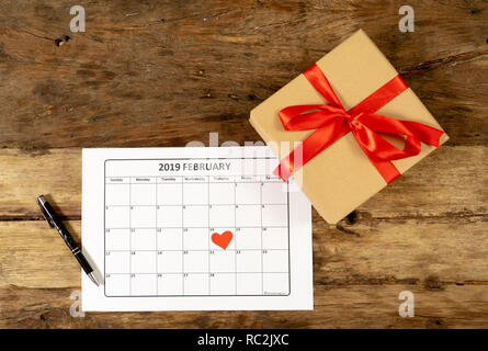 Conceptual image of 2019 february calendar and present gift wrapped with red ribbon on rustic vintage table in getting ready for saint Valentines day  Stock Photo